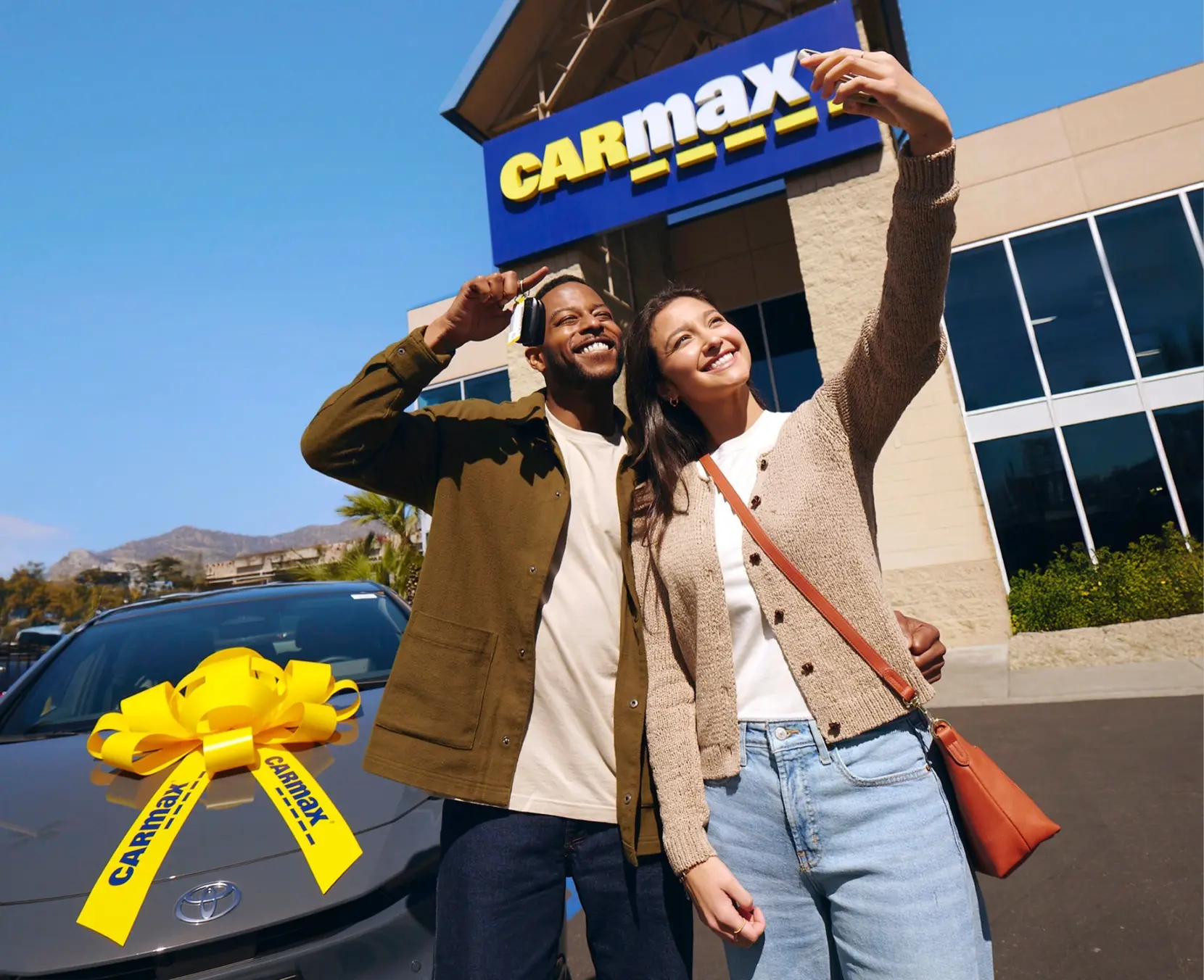 Two customers take a selfie with their recently bought used car