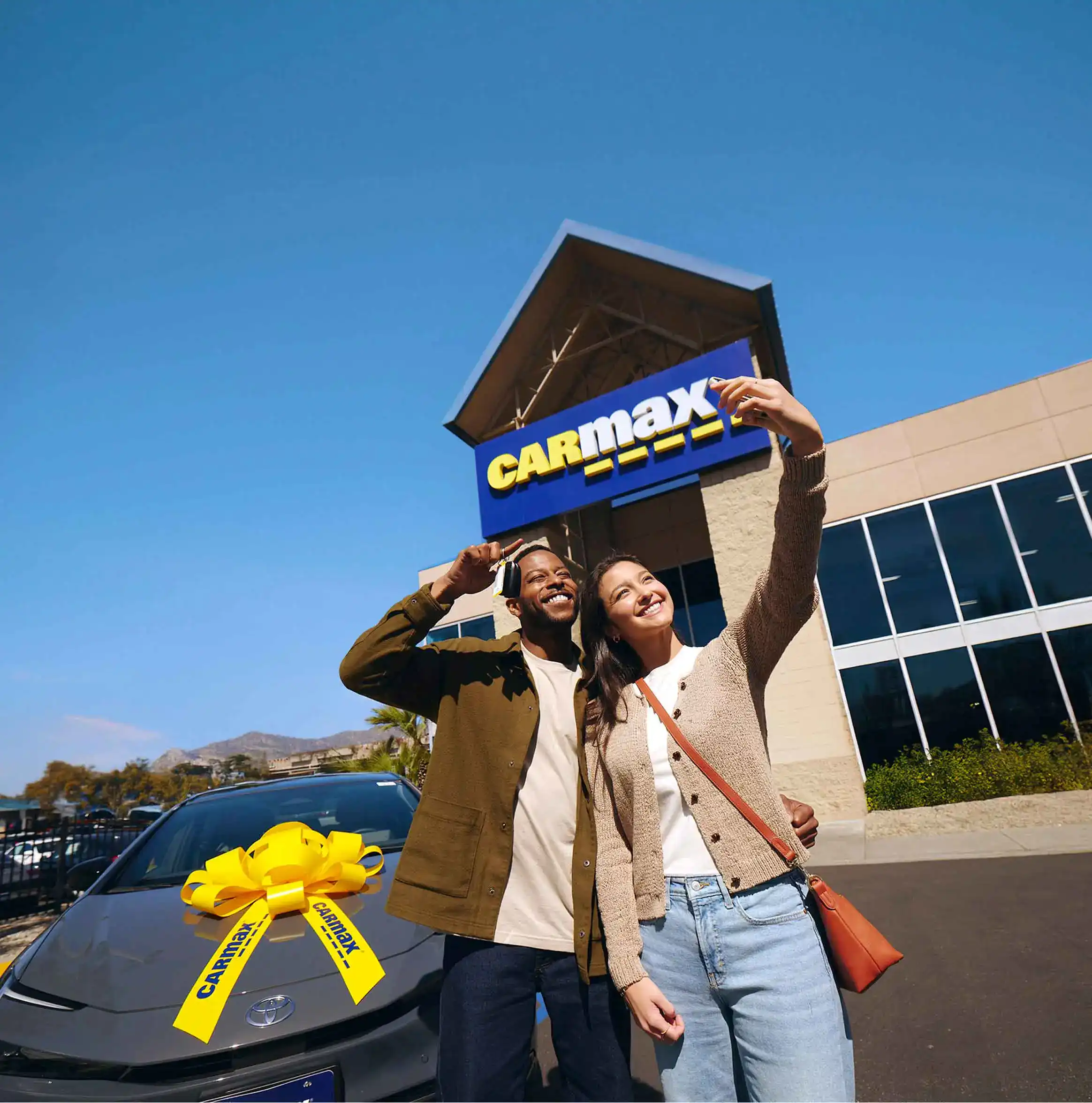 Two customers take a selfie with their recently bought used car